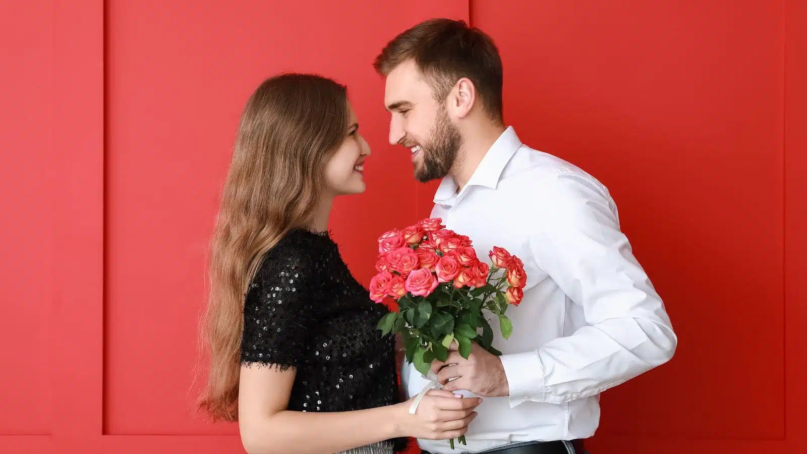 happy couple with flowers in front of a red wall