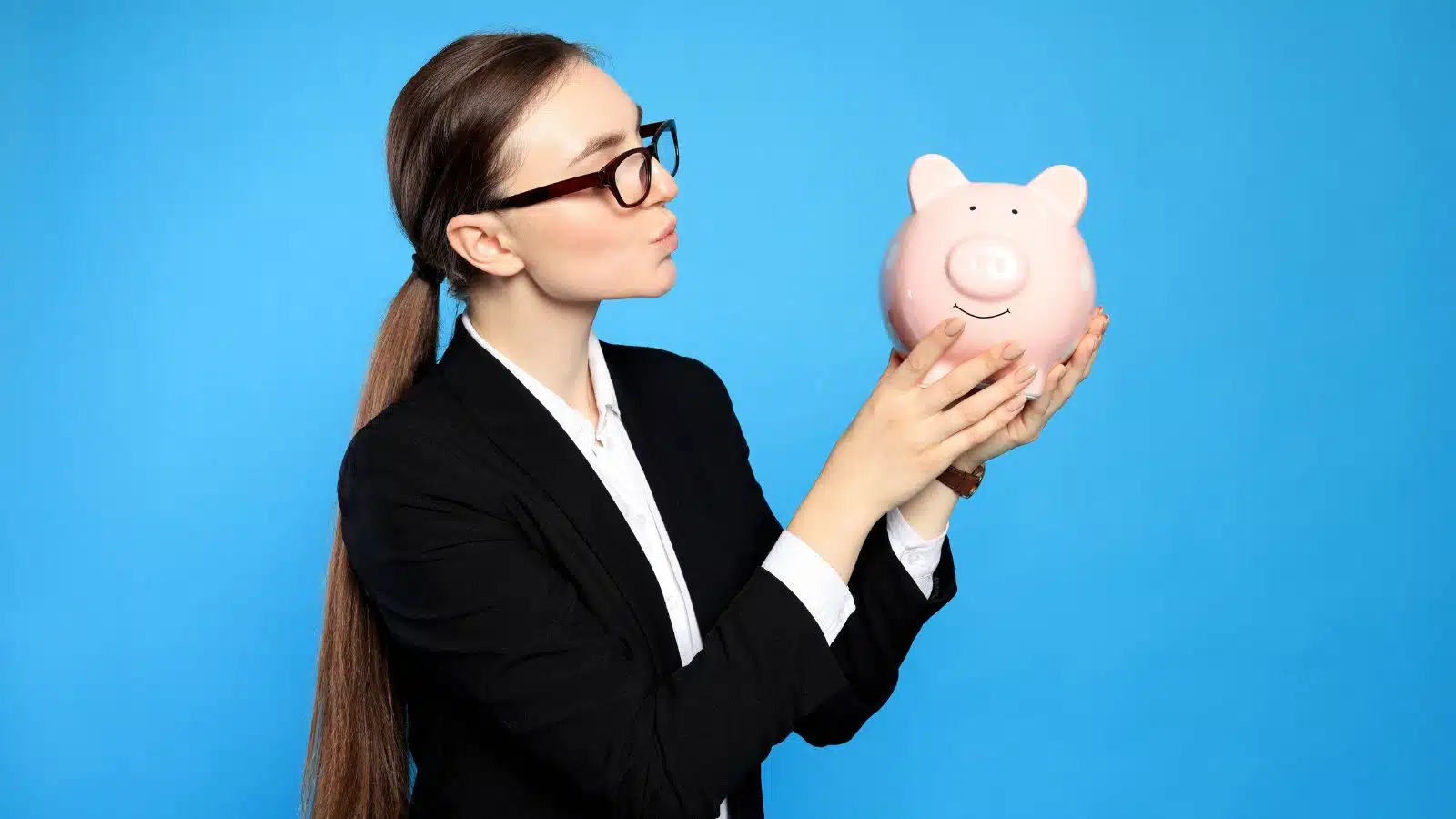a young woman holding a piggy bank on a blue background