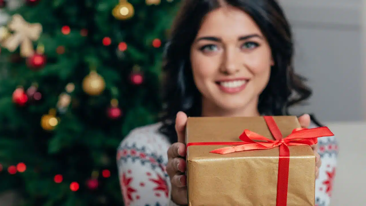 woman giving Christmas gift looking forward