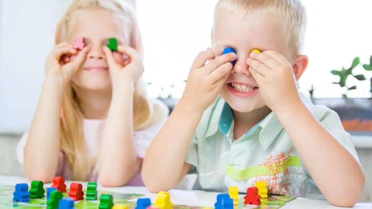 little blonde girl and boy have fun, laugh and indulge playing board game