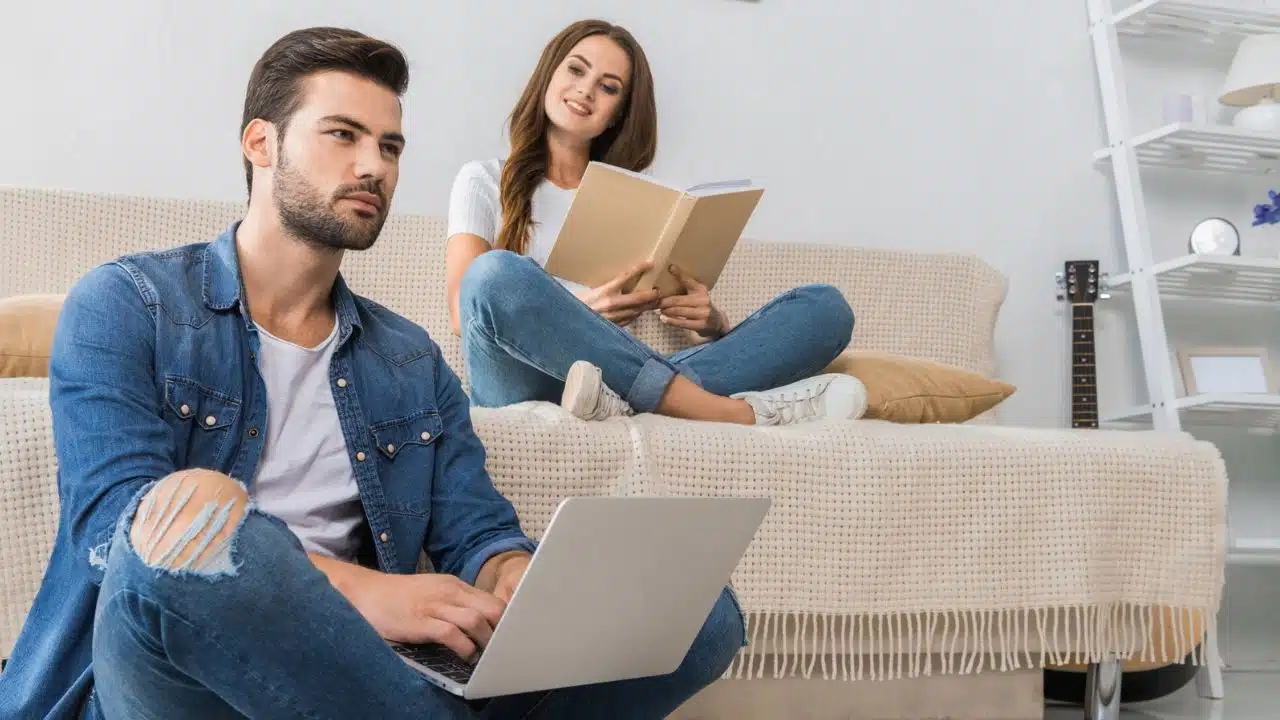 couple with book and laptop at home studying