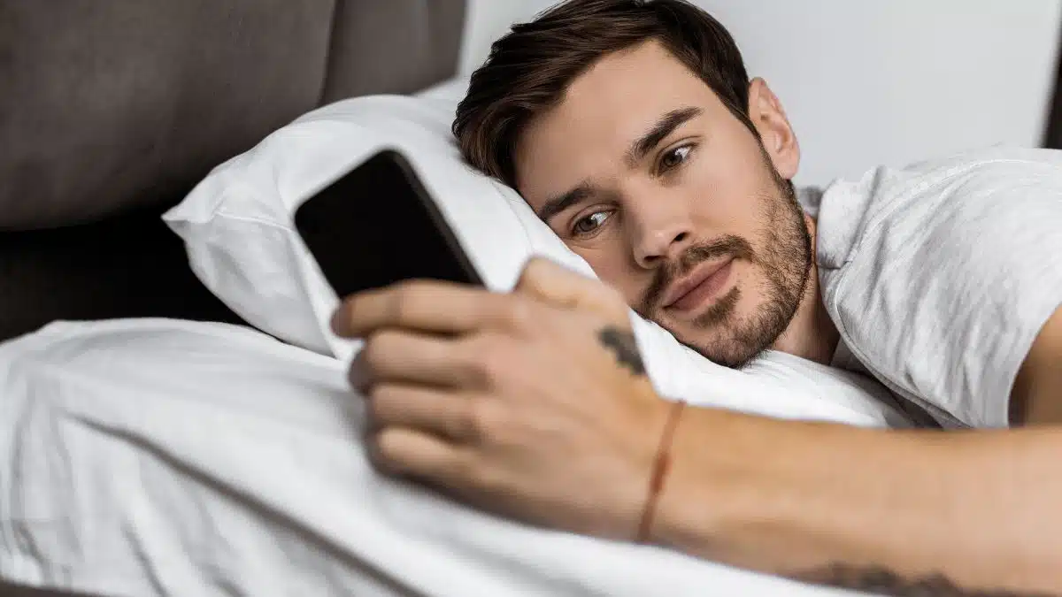 handsome man looking at cell phone in bed