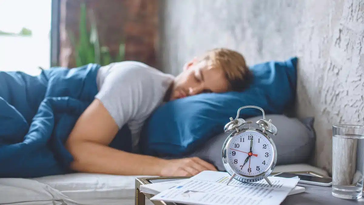 man sleeping with alarm clock