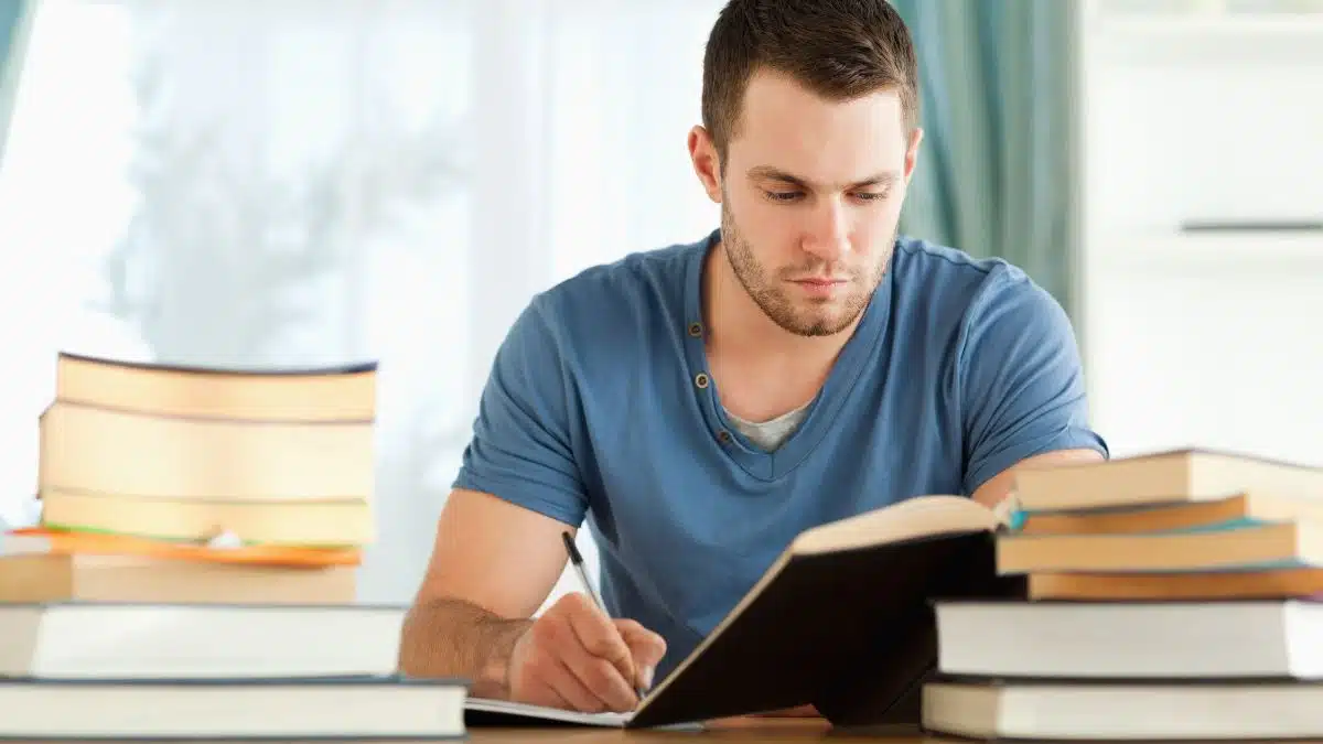 man studying at a desk surrounded by text books