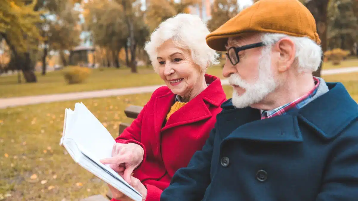 older couple reading on park bench