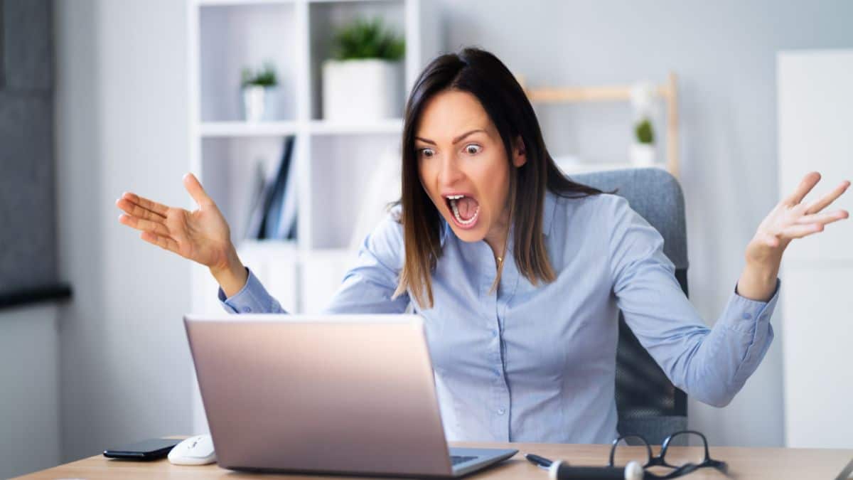 woman angry reading bad news on a laptop at work