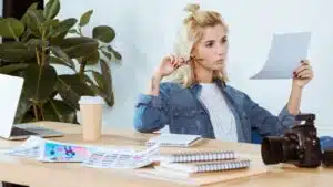 young woman with paperwork thinking at her desk