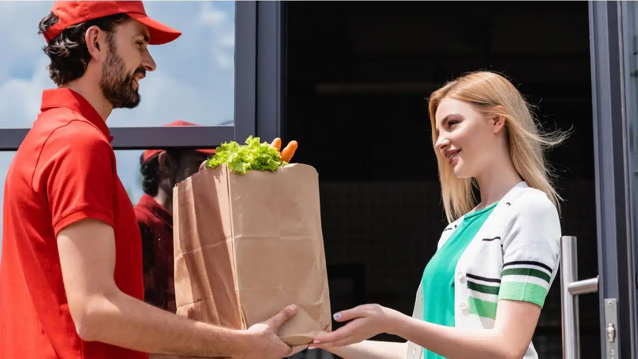 man delivering bag of groceries to young woman