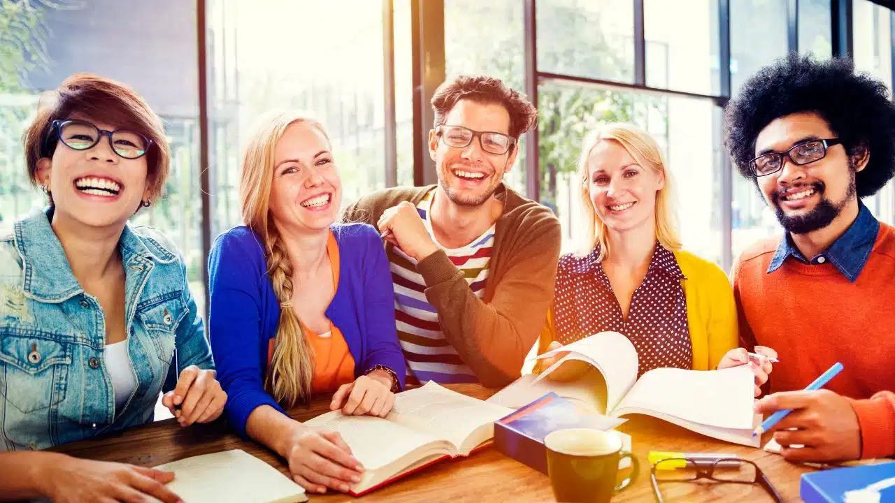 happy multicultural coworkers together at a desk with books