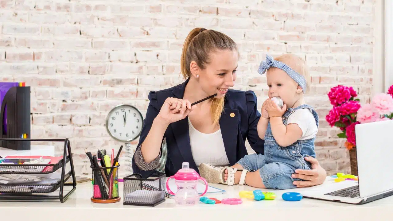 happy wfh mom with baby at her desk