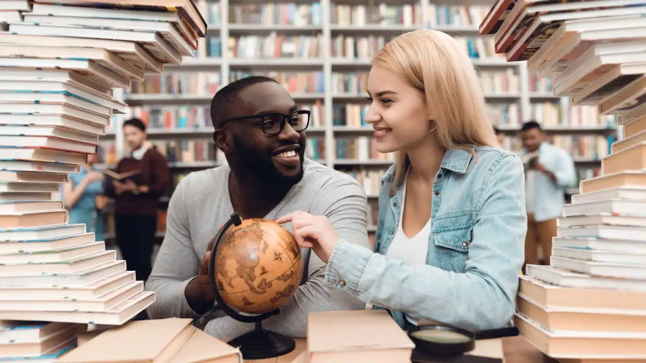 people with globe in library surrounded by books