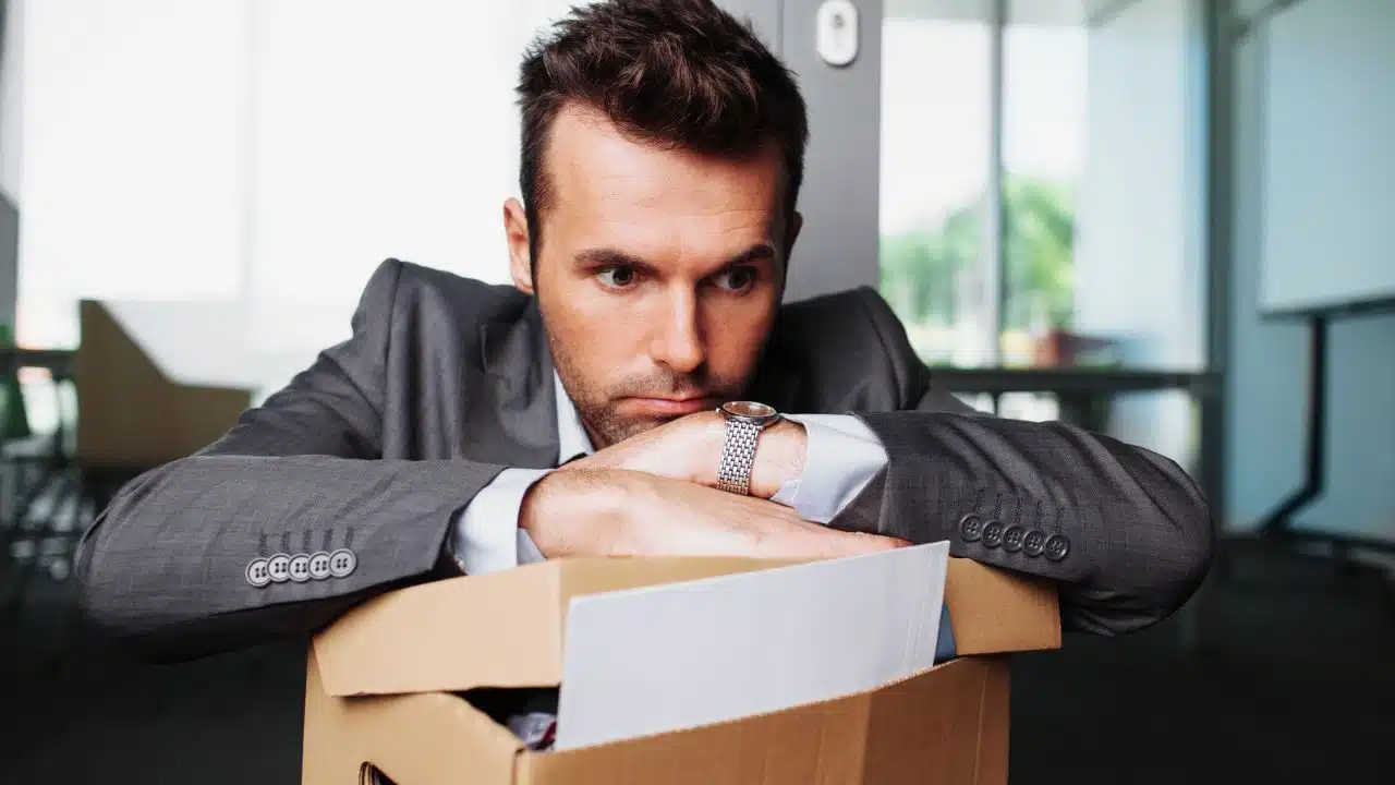 sad fired man close up with box of belongings