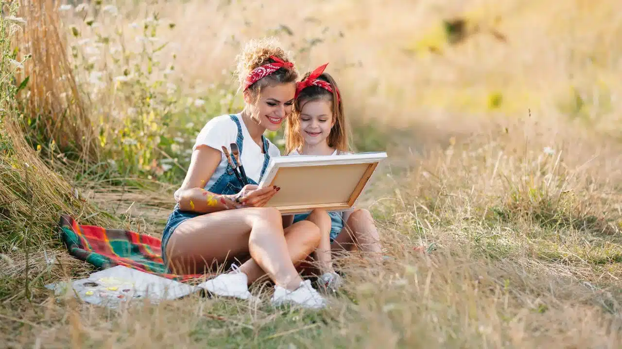 young woman and girl outside painting on a canvas