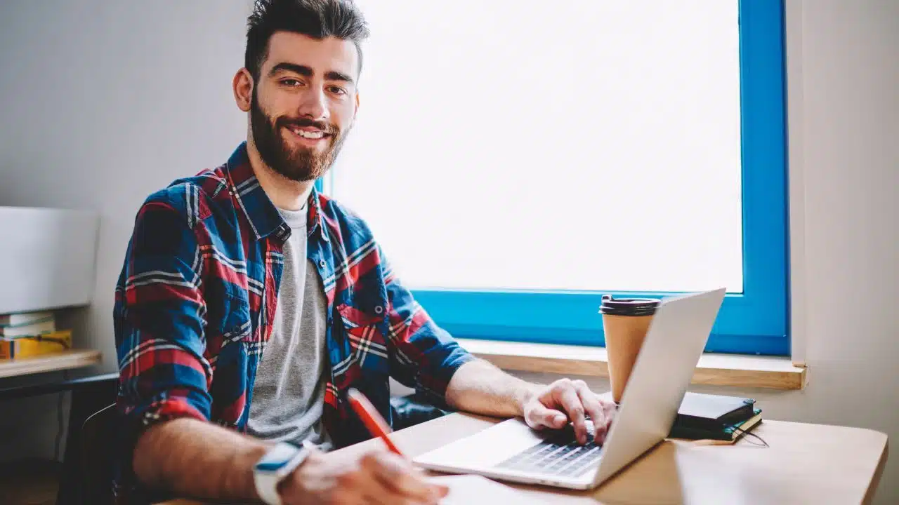 man taking notes at laptop