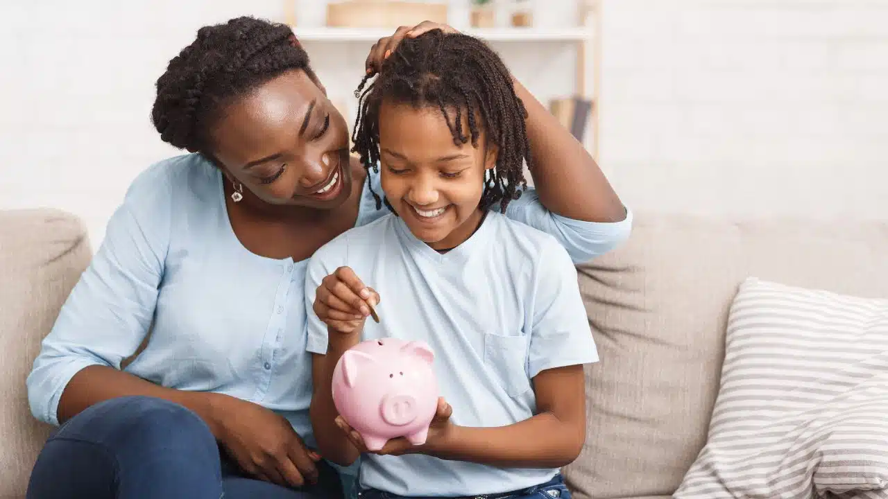 mother and daughter putting money in piggy bank
