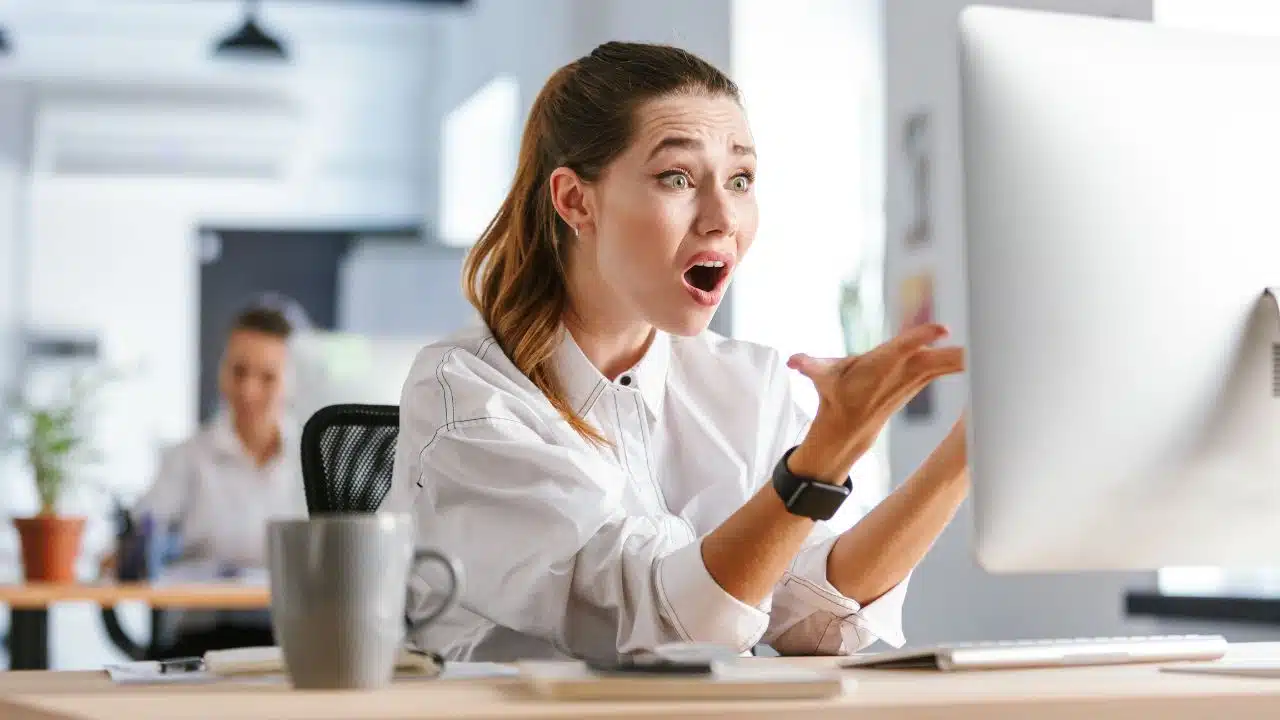shocked office worker looking at computer screen in office