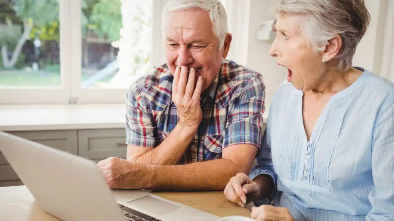 shocked senior couple looking at laptop at home