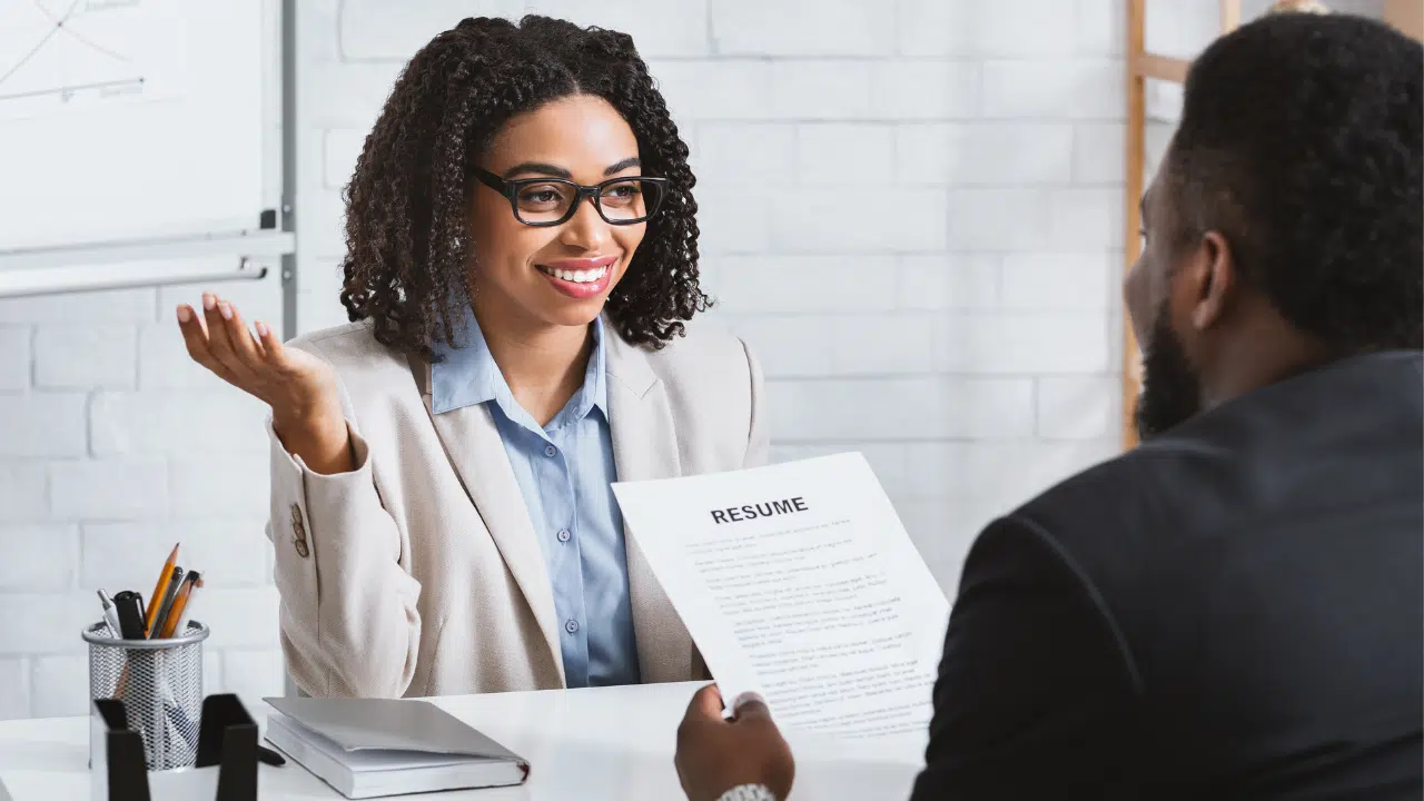man interviewing woman with resume in office