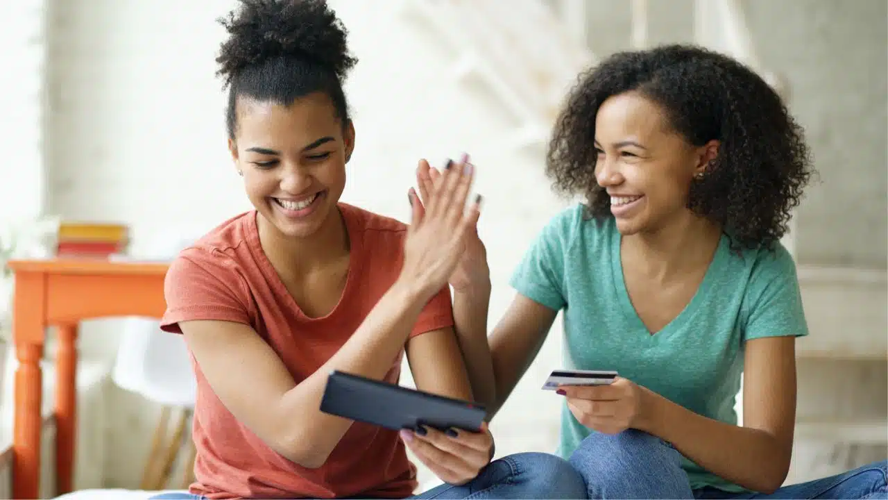 cheerful teens with credit card shopping from home
