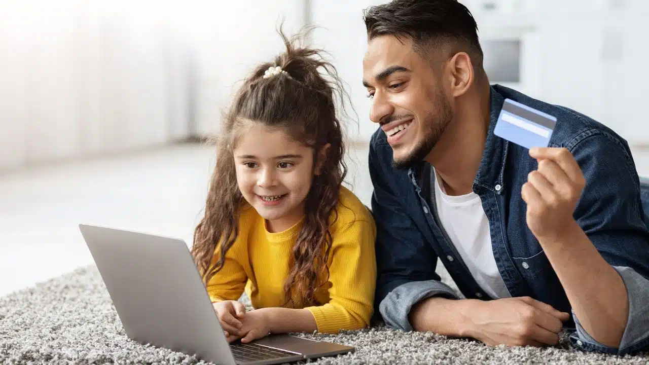 dad and daughter with laptop and bank card