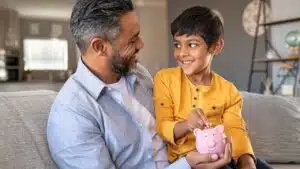 father and son putting coin in piggy bank