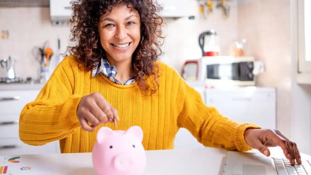 woman saving money with piggy bank at home