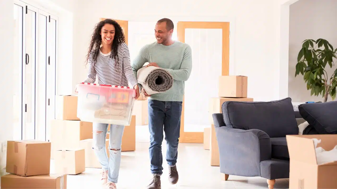 couple carrying boxes in new home