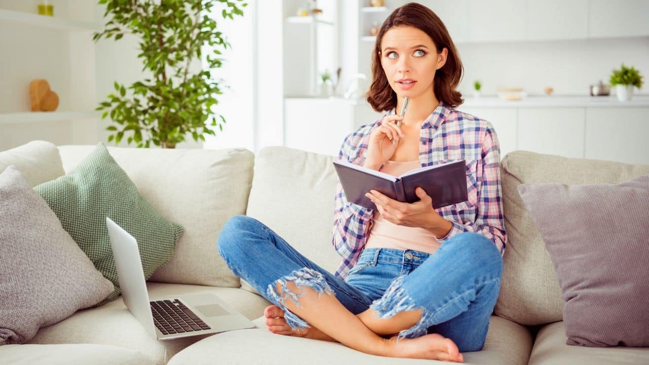 woman thinking about what to write in notebook at home