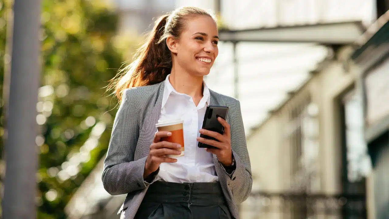 woman walking on break with coffee and phone in hand