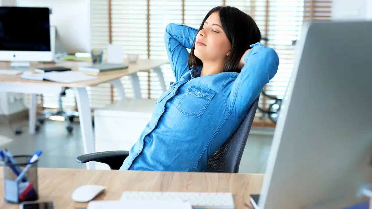 woman with eyes closed relaxing at desk