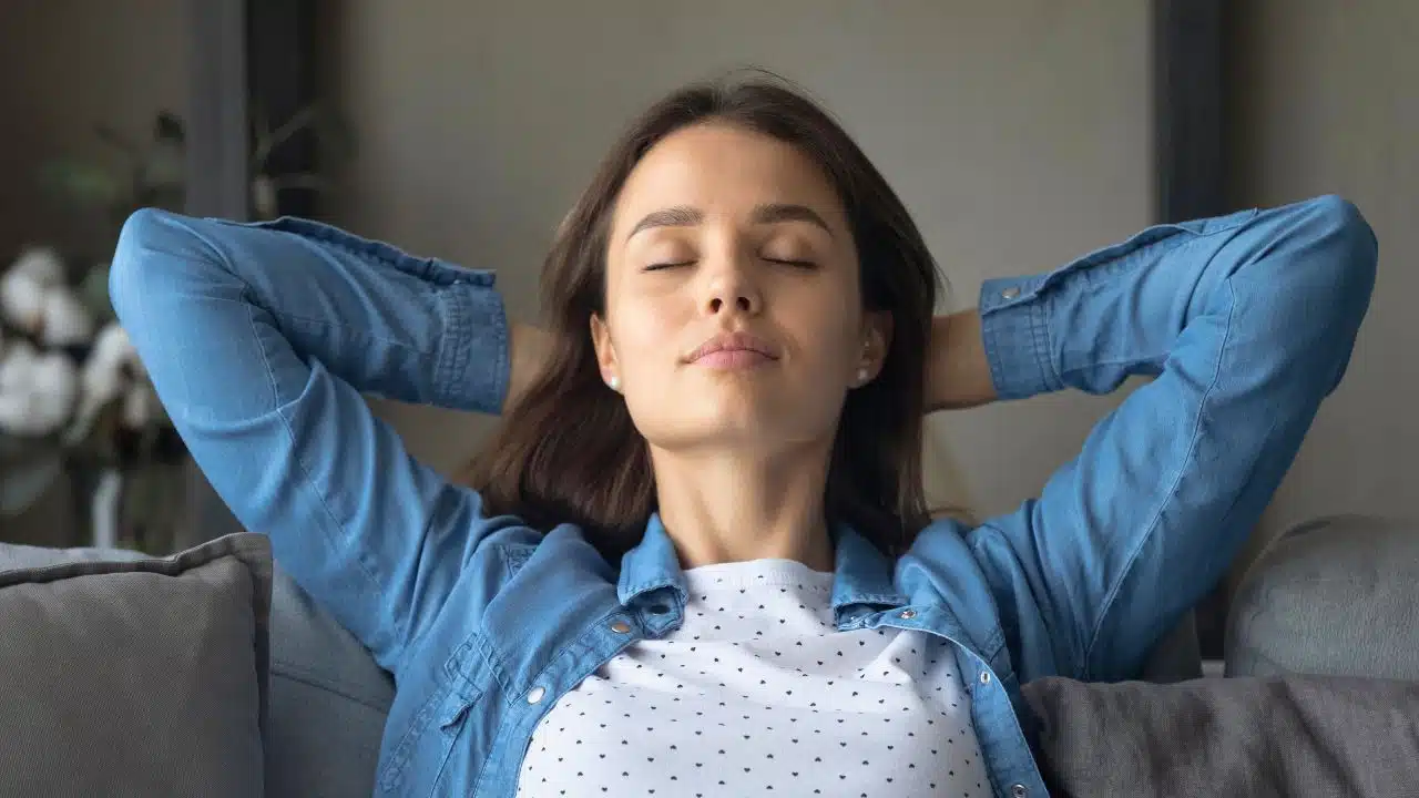 woman with eyes closed relaxing at home on couch