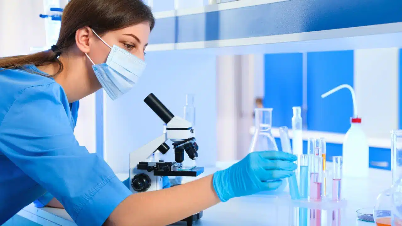 Scientist working with microscope and test tubes