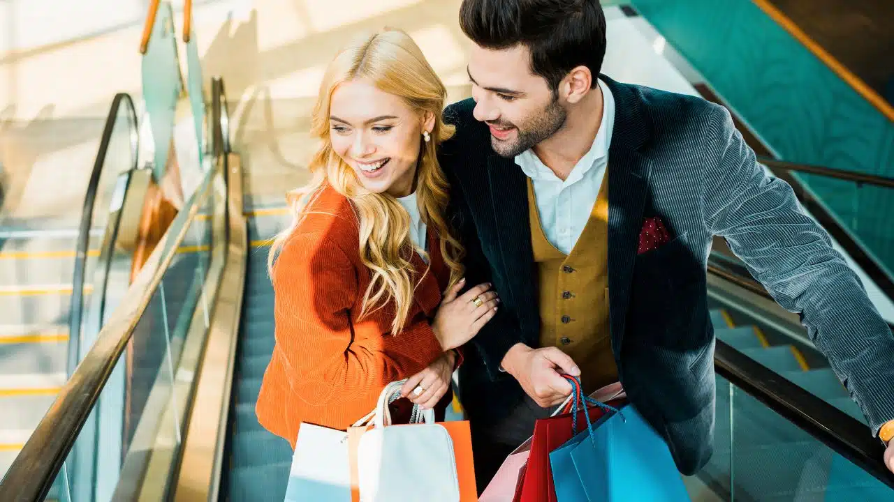 couple at mall with shopping bags on escalator