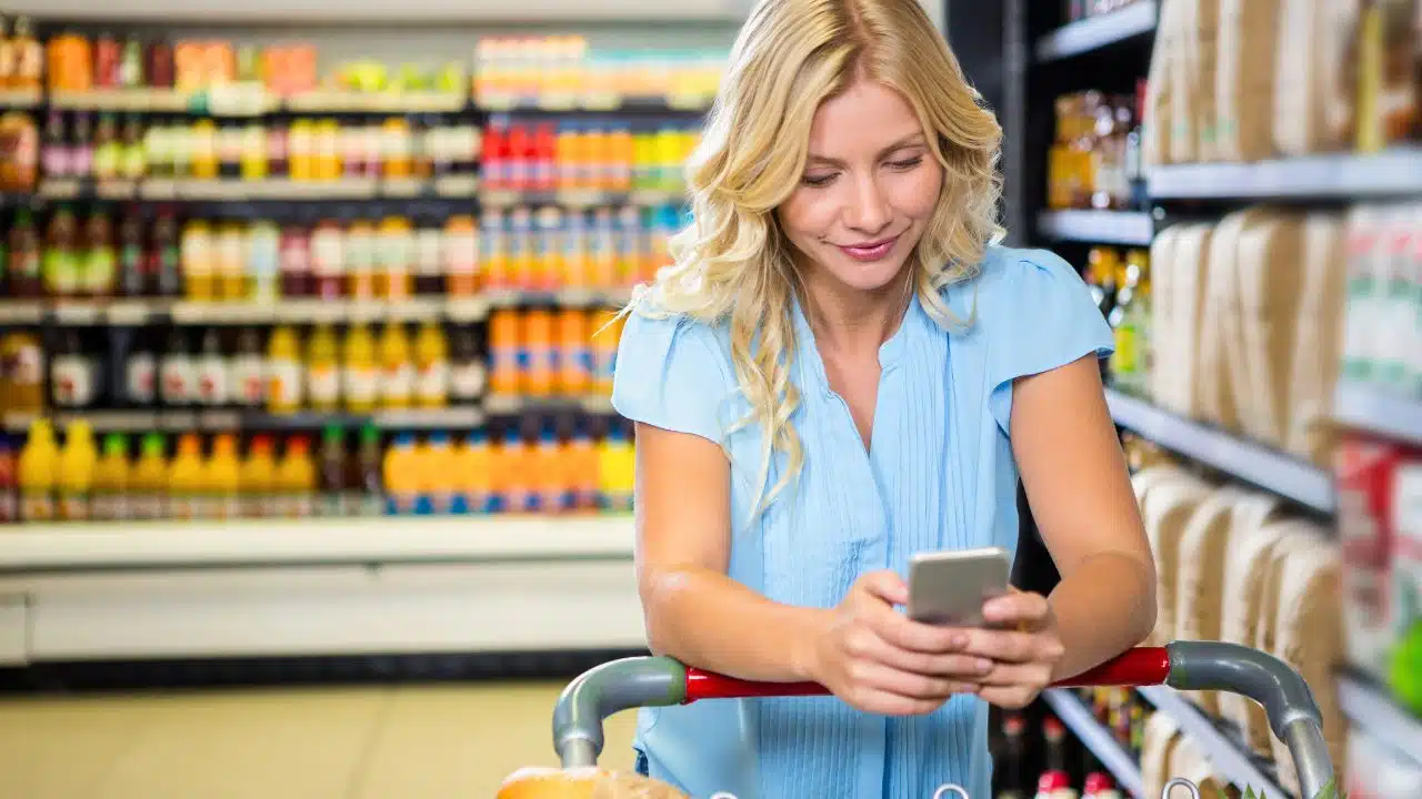 woman shopping in supermarket using her phone