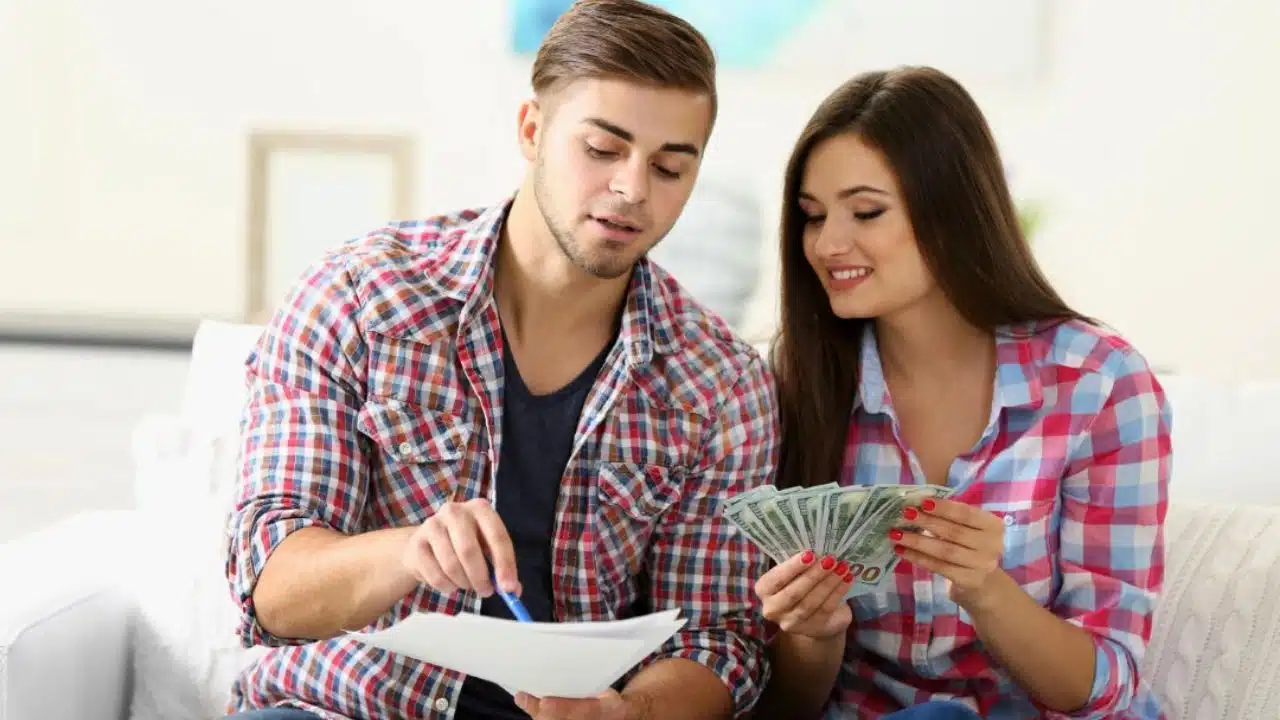 young couple with cash looking at paperwork