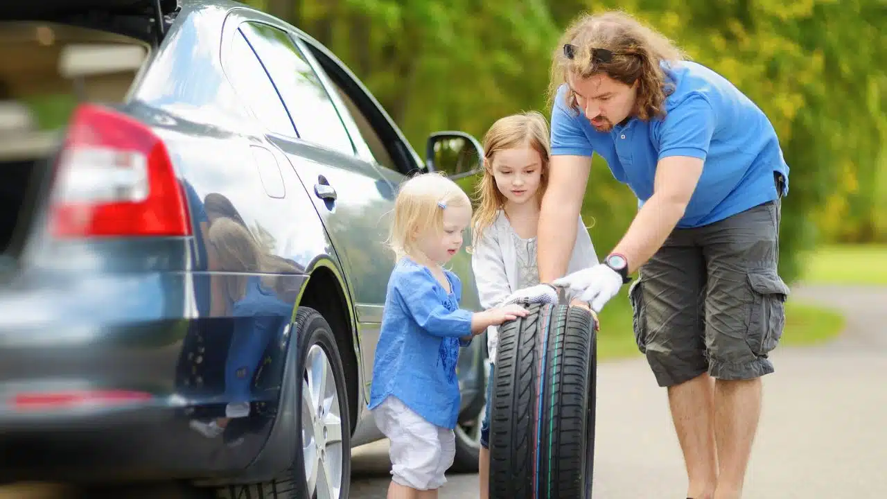 young girls helping dad change a flat tire