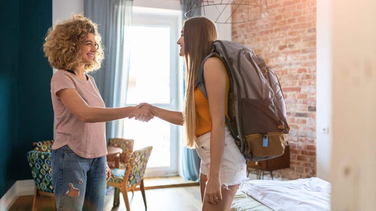 young traveler checking in to hostel room with backpack