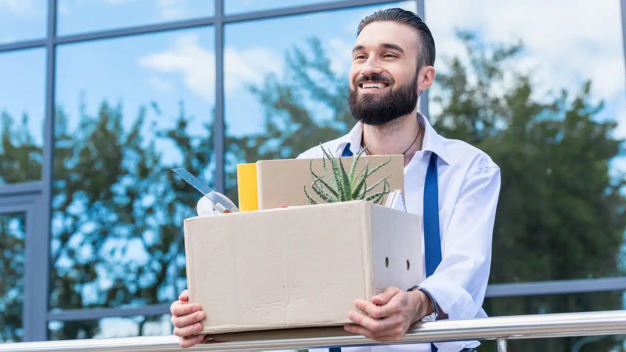 happy man leaving his job with box of belongings