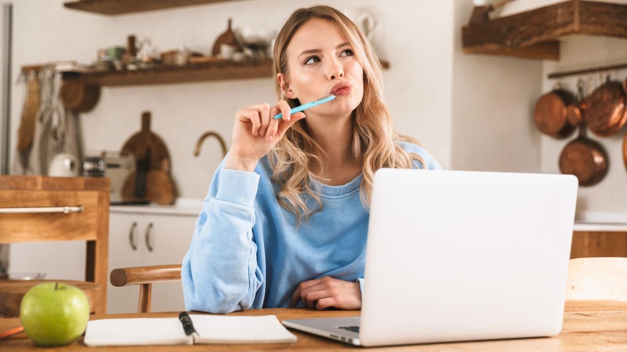 young woman at laptop thinking