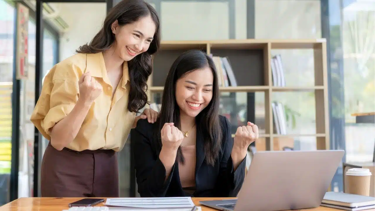 happy businesswomen working in office together at laptop