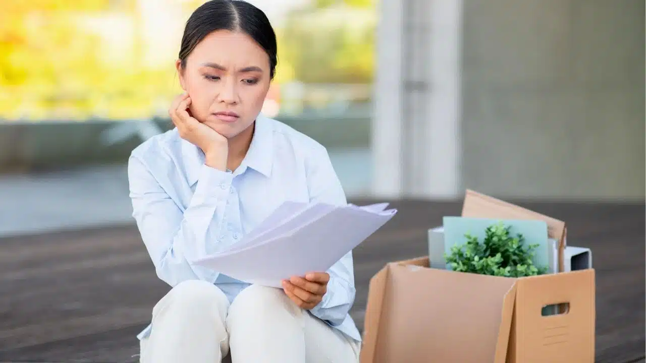 sad woman just fired with belongings in a box next to her