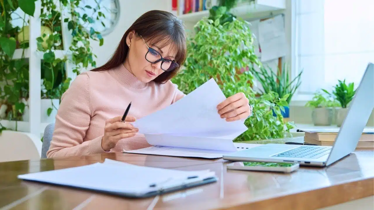 woman with paperwork in office with lots of plants